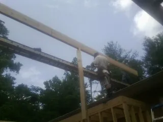 Carpenter setting a ridge beam over a new addition frame — Ice Dam Removal by Roofing Brothers in Port Jefferson Station