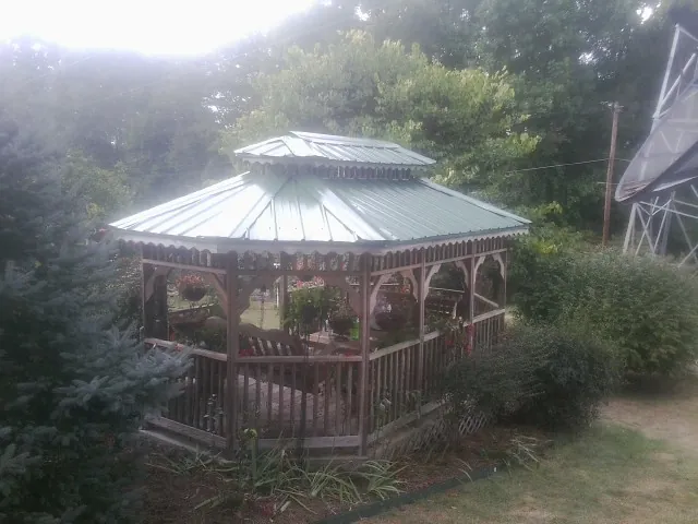 Green metal roof on a backyard gazebo surrounded by garden beds in Port Jefferson Station