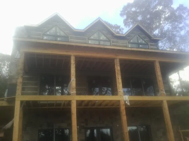Dormers and porch framing on a large log home under construction — Roof Coating work by our crew in Port Jefferson Station