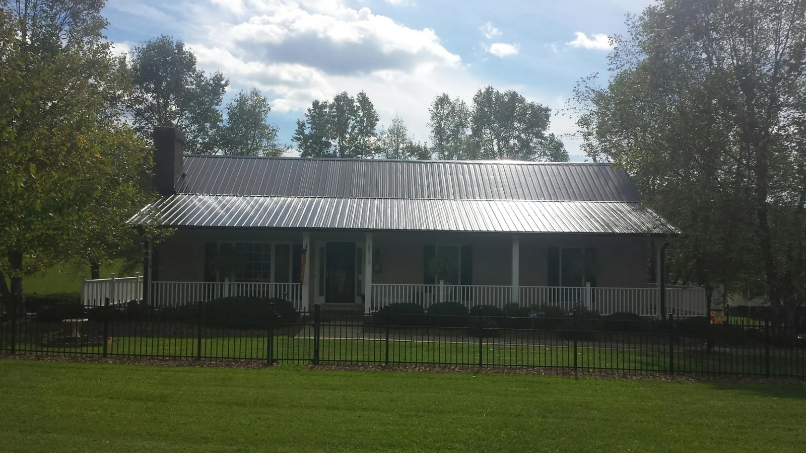 Gray metal roof on a brick ranch with a full width front porch — Gutter Guard Installation work by our crew in Port Jefferson Station