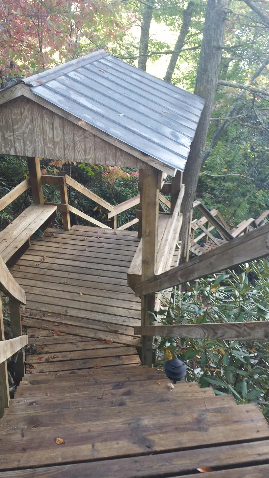 Metal roofed shelter over wooden steps on a wooded walkway — Skylight Repair & Installation work by our crew in Port Jefferson Station