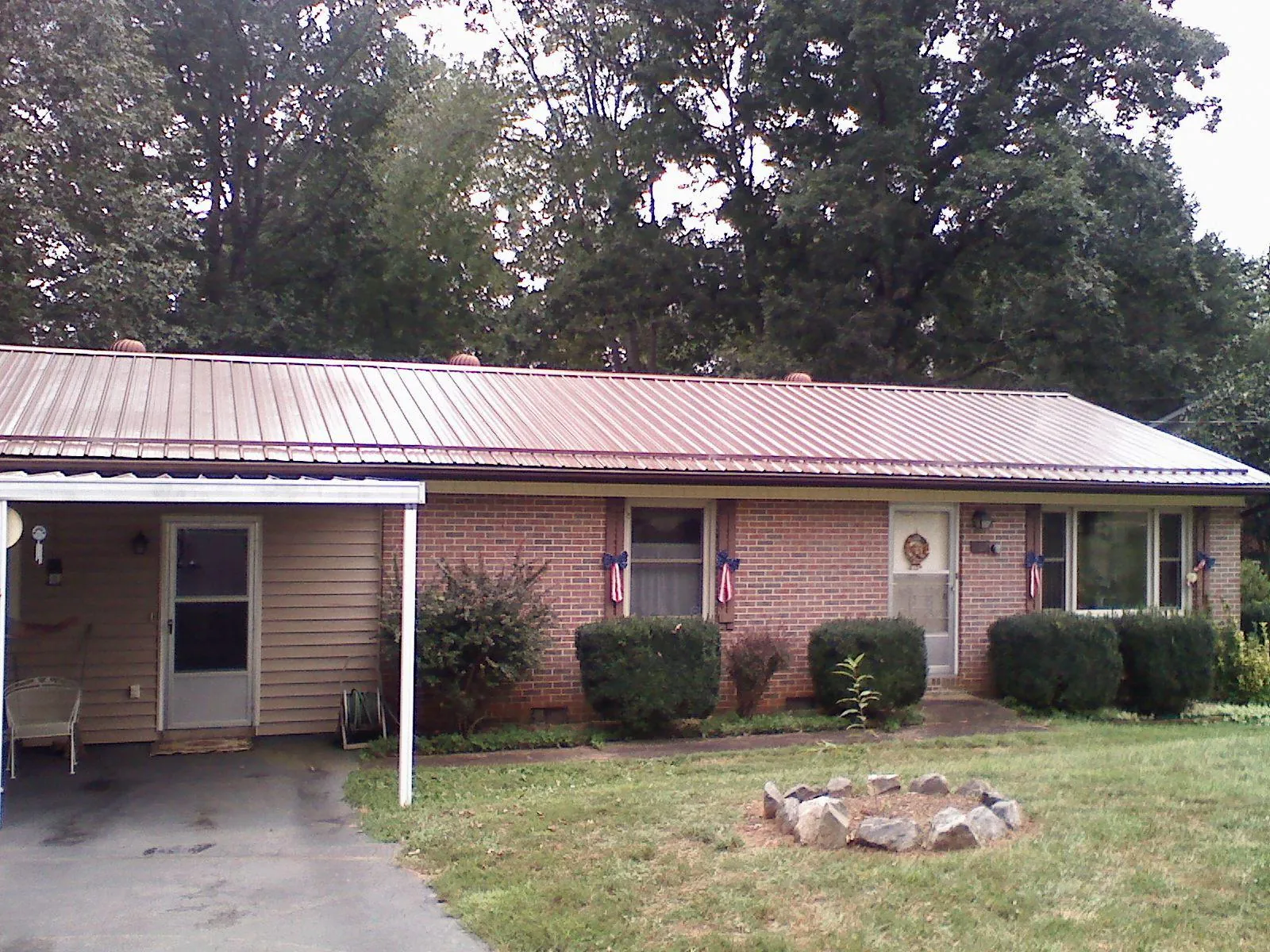 Bronze metal roof and carport on a brick ranch home — Roof Repair work by our crew in Port Jefferson Station