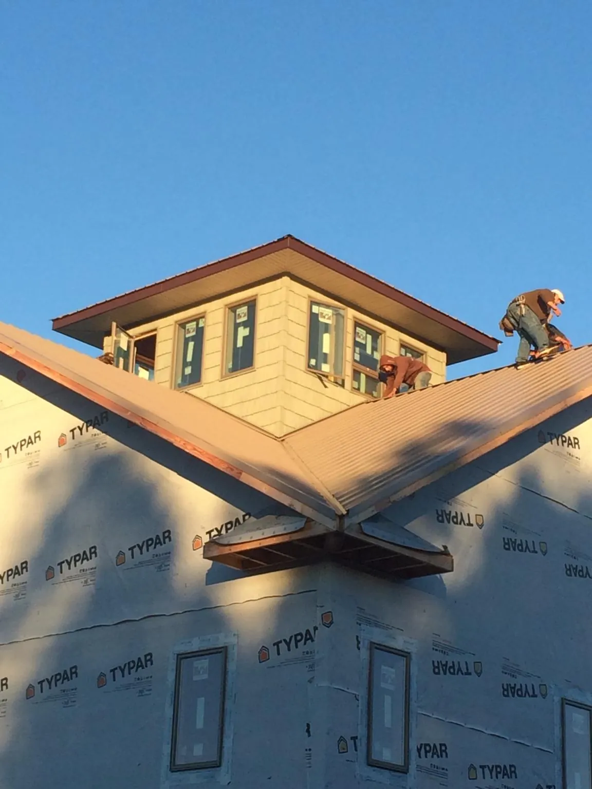 Roofers working around a rooftop cupola on a new metal roof at sunset — Roof Waterproofing in Port Jefferson Station by Roofing Brothers